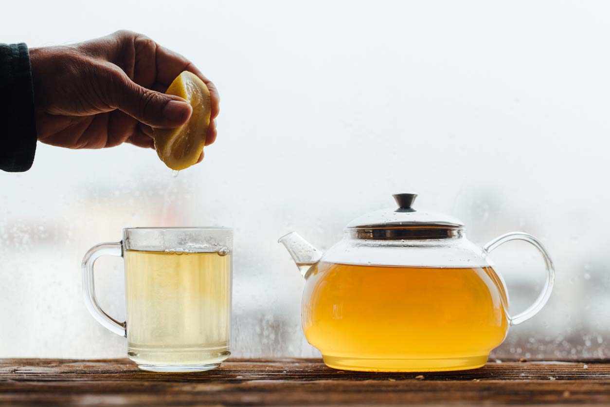 hand squeezing lemon with green tea pot and mug