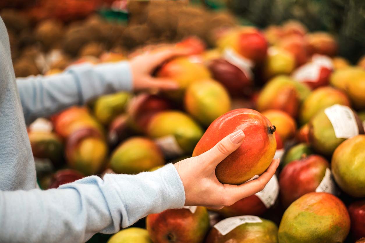 young woman choosing fresh mango in market