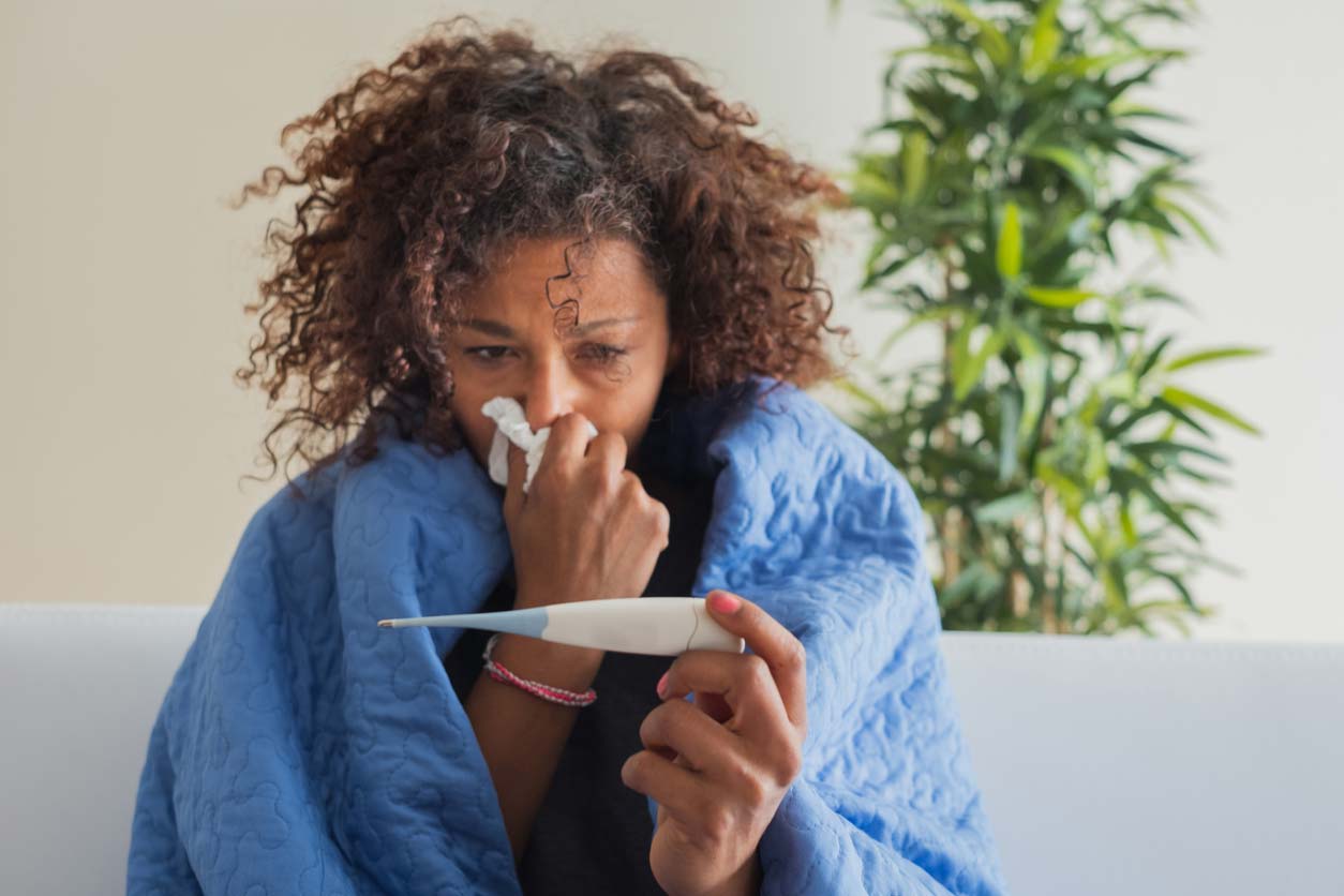 woman blowing nose and checking body temperature