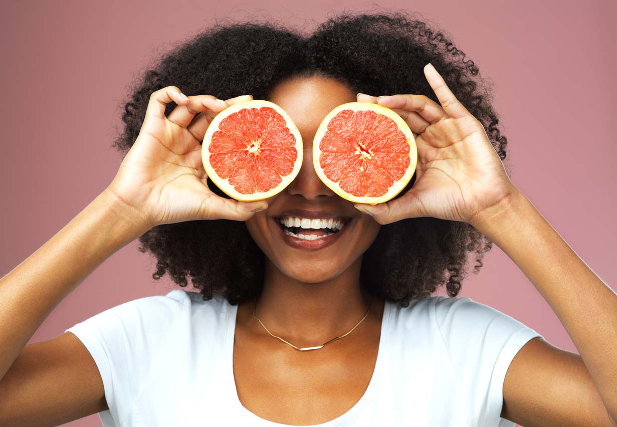 Woman holding grapefruit halves in front of eyes