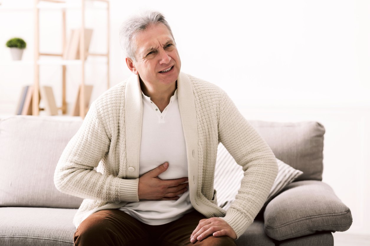 Terrible stomachache. Senior man hugging his belly, suffering from pain