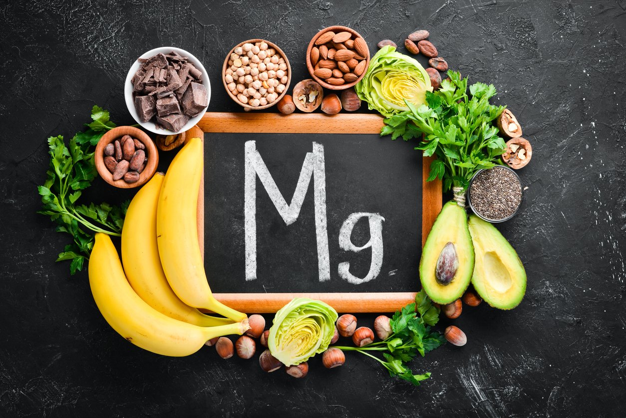 Foods containing natural magnesium. Mg: Chocolate, banana, cocoa, nuts, avocados, broccoli, almonds. Top view. On a black background.