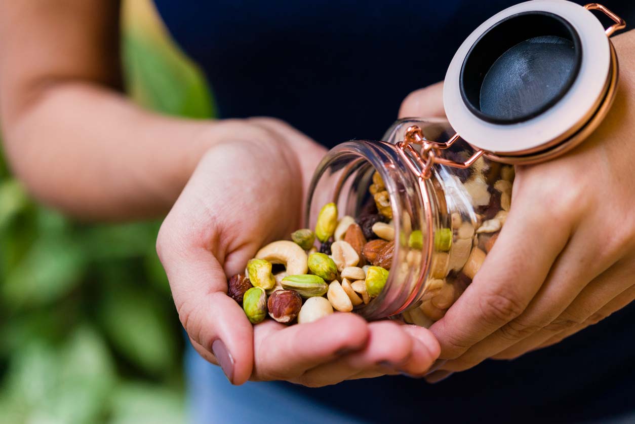 Person pouring mixed nuts out of jar into hand