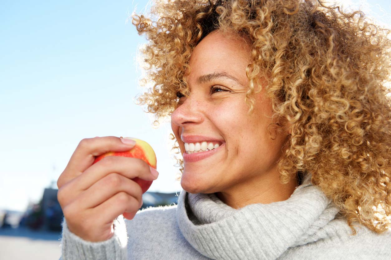 woman smiling and holding an apple