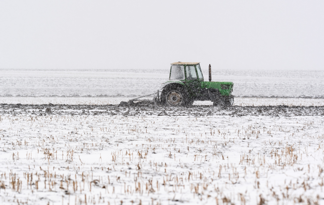Tractors plowing stubble fields during winter
