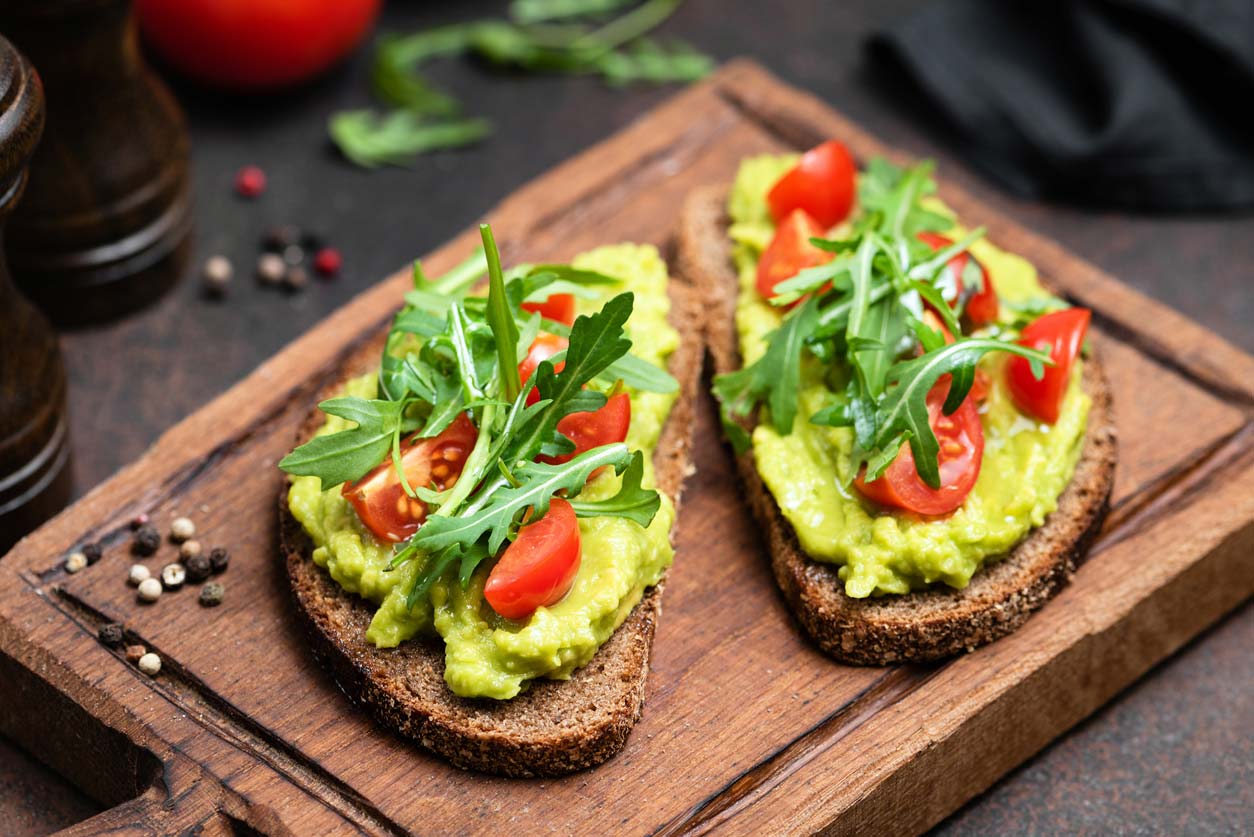 avocado toast with tomato and arugula garnish