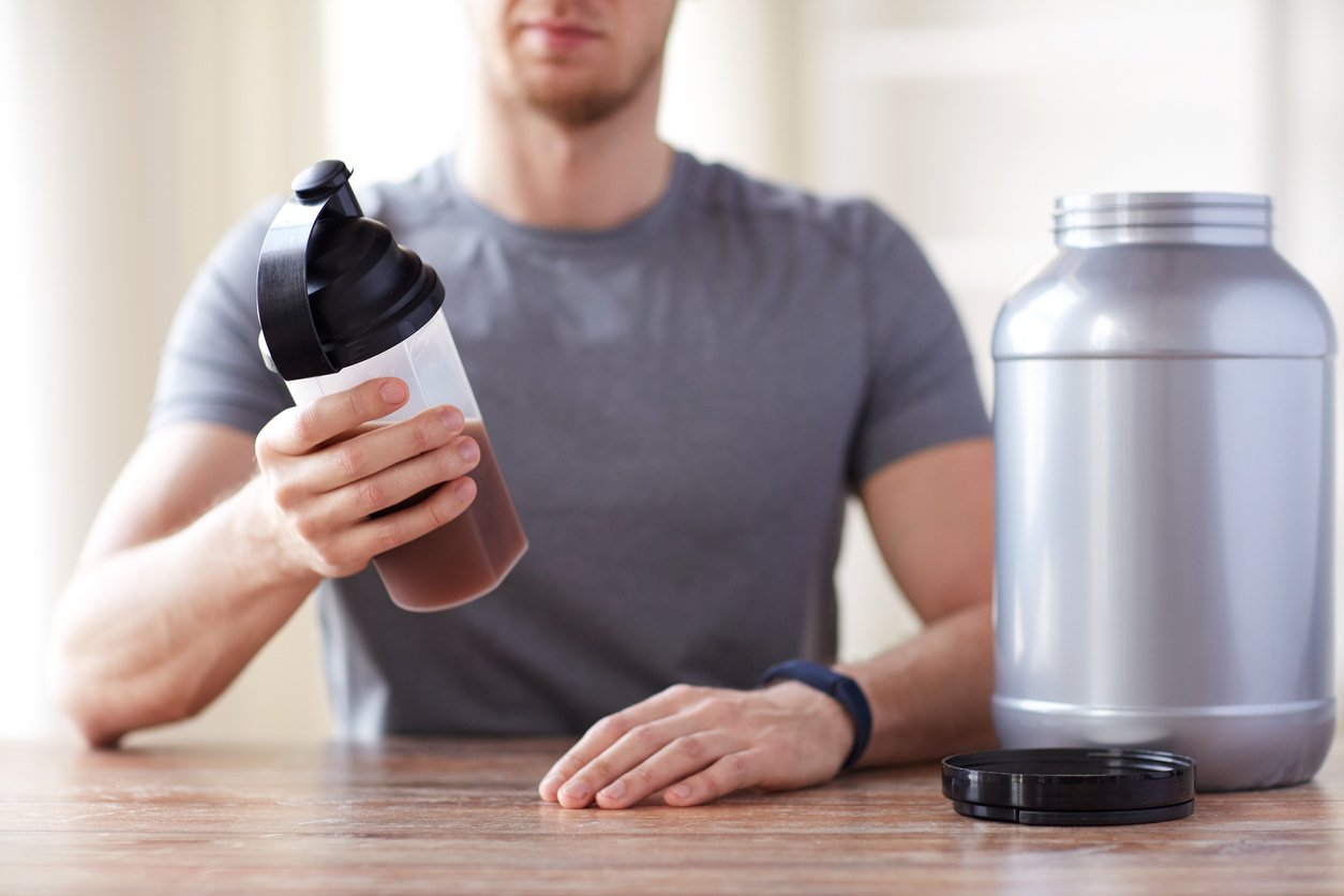 close up of man with protein shake bottle and jar