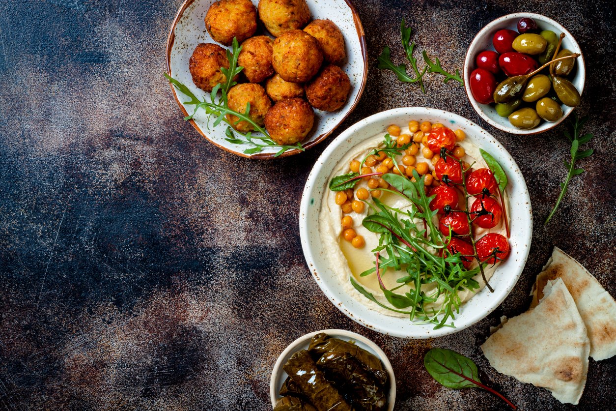 Arabic traditional cuisine. Middle Eastern meze with pita, olives, hummus, stuffed dolma, falafel balls, pickles. Mediterranean appetizer party idea