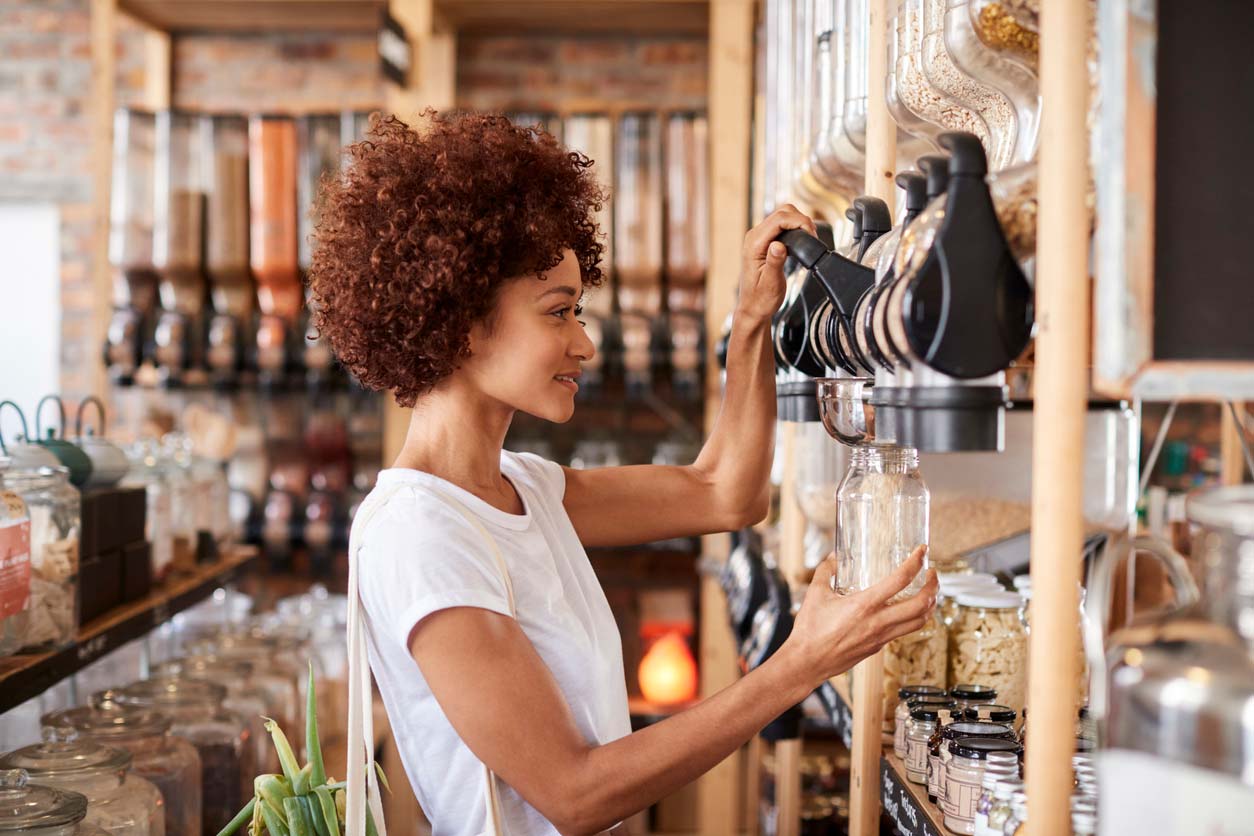 Woman filling a glass container in the bulk foods section of a store