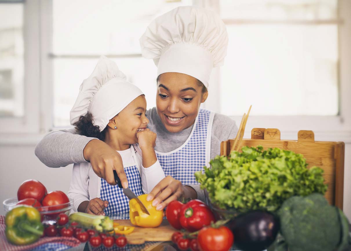 mother and daughter in chef hats making healthy food