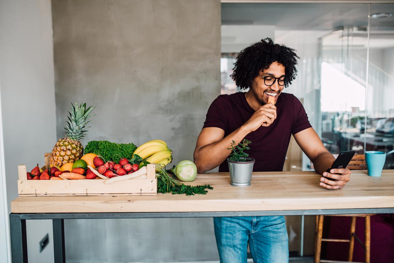 man eating carrot using phone