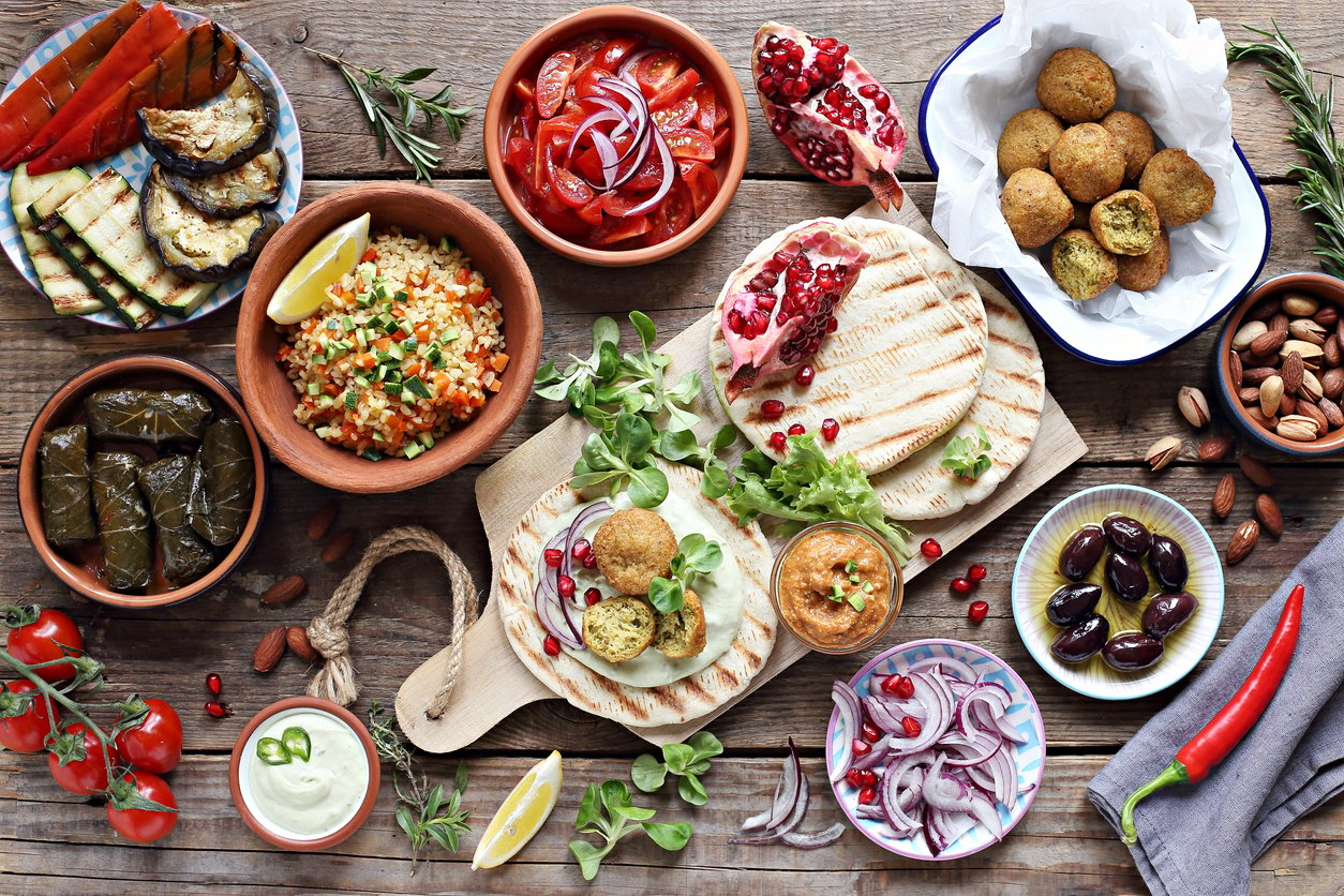 Middle eastern, arabic or mediterranean appetizers table concept with falafel, pita flatbread, bulgur and tomato salads, grilled vegetables, stuffed grape leaves,olives and nuts.