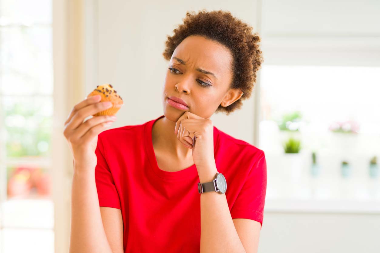 woman contemplating sugary treat