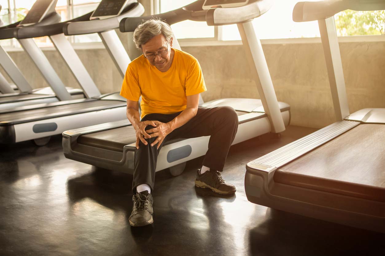 Vitamin D health benefits include bone health: Man holding his knee while sitting on treadmill