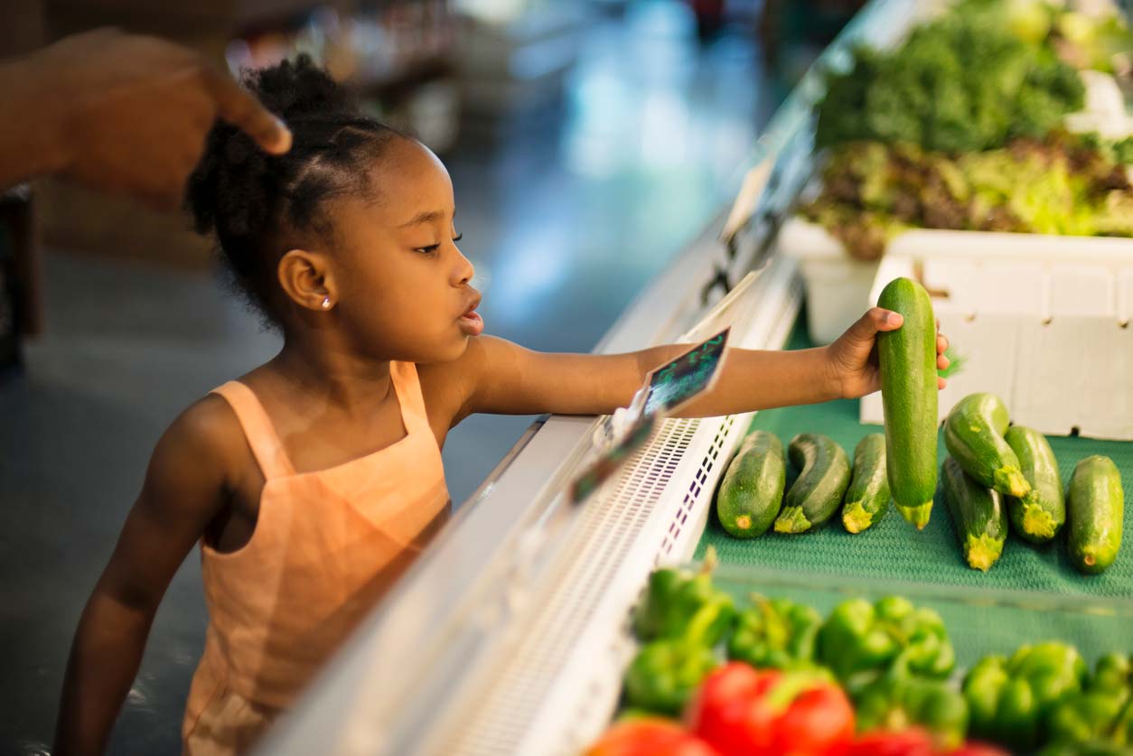 A child picks out a zucchini 