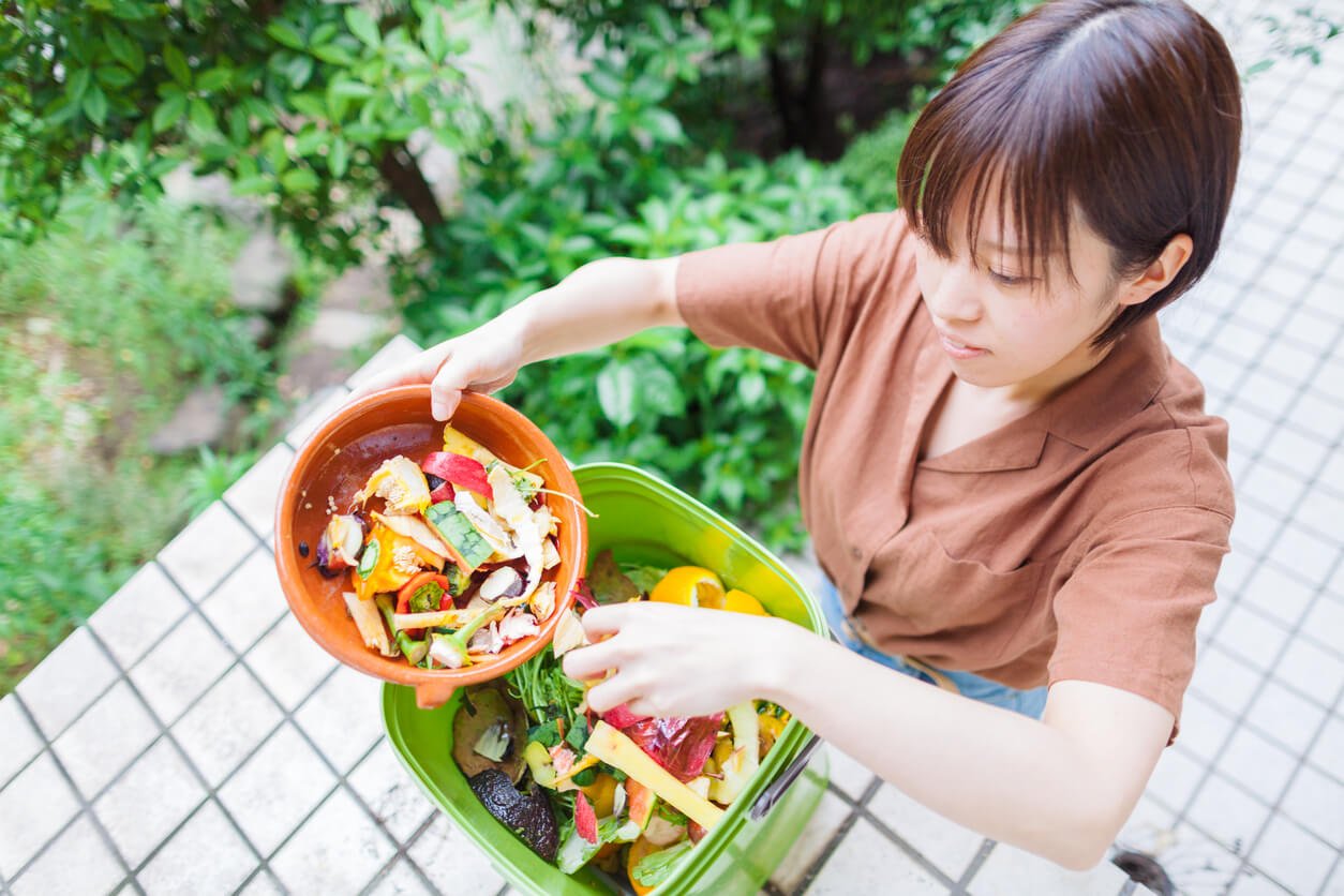 woman putting garbage into composter