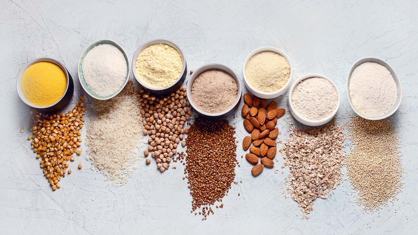 various gluten-free flours in bowls next to source grain or nut