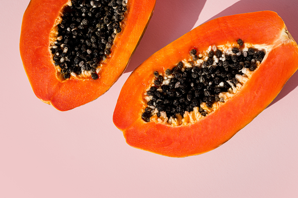 Fresh papaya exotic tropical fruit on pink background. Sun day light illumination. Minimalistic summer flat lay wallpaper. Creative food concept. Copy space template.