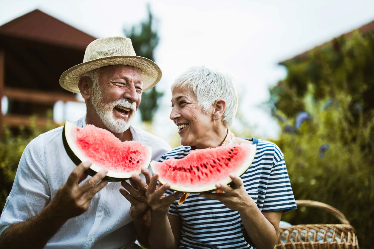 elderly couple enjoying watermelon together