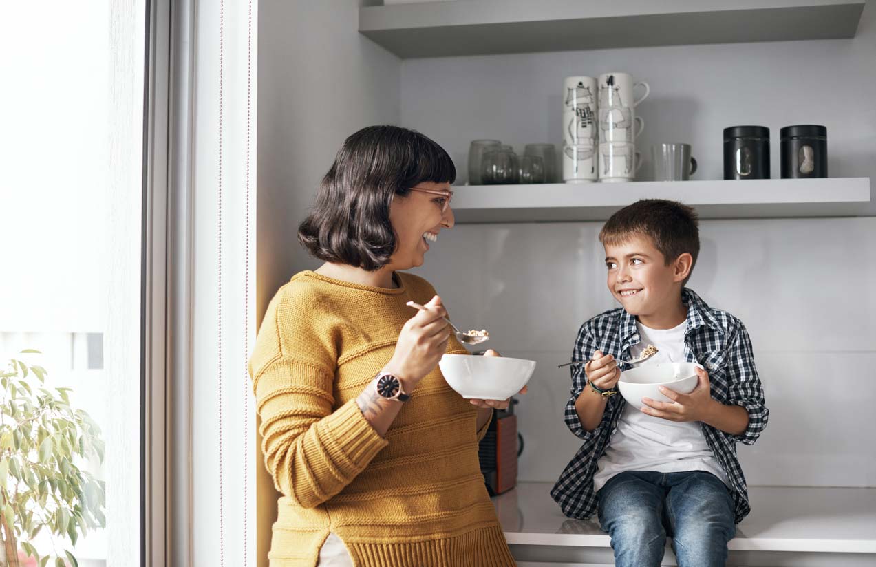 Happy mother and son eating oatmeal