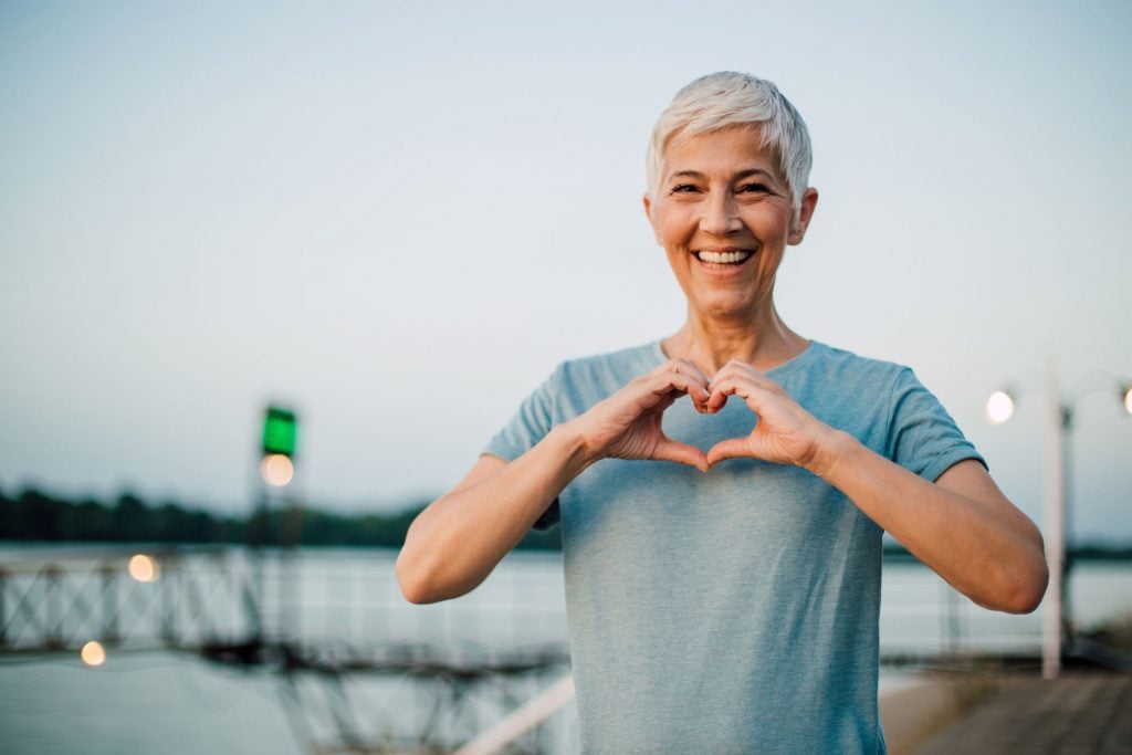 older woman making a heart with her hands
