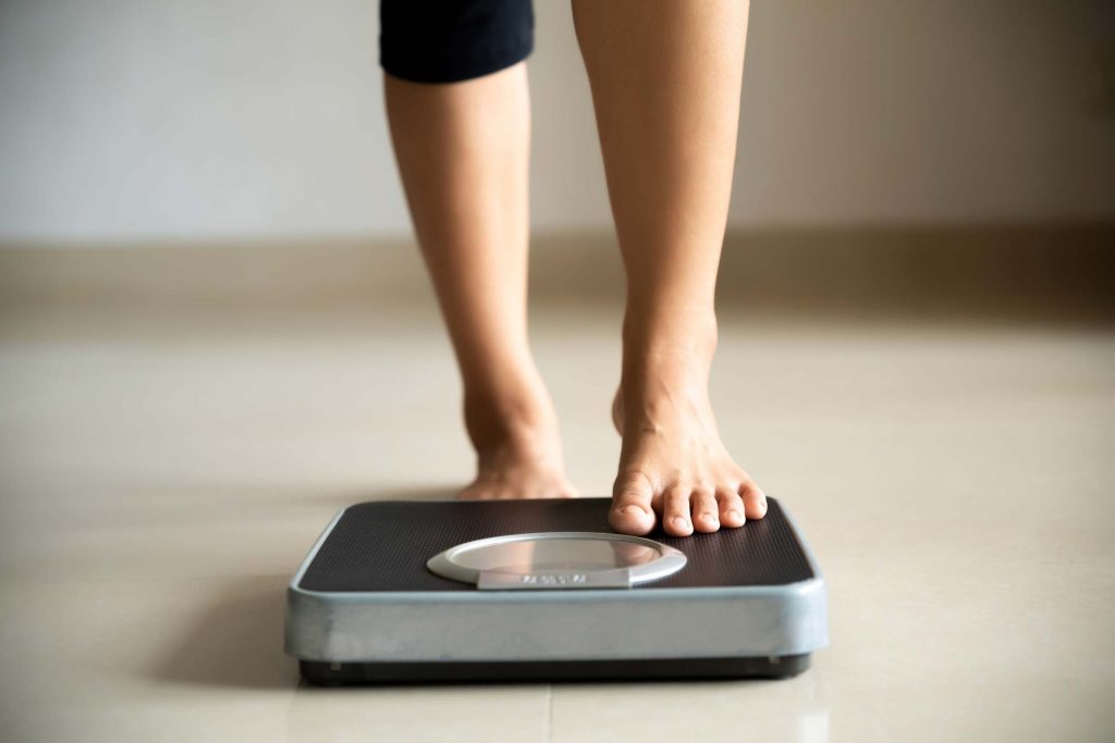 Woman stepping on to scale to measure weight