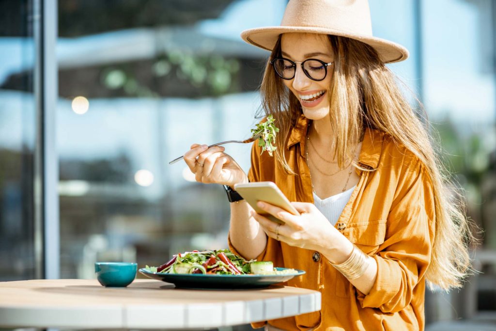 Woman eating a salad and looking at her phone