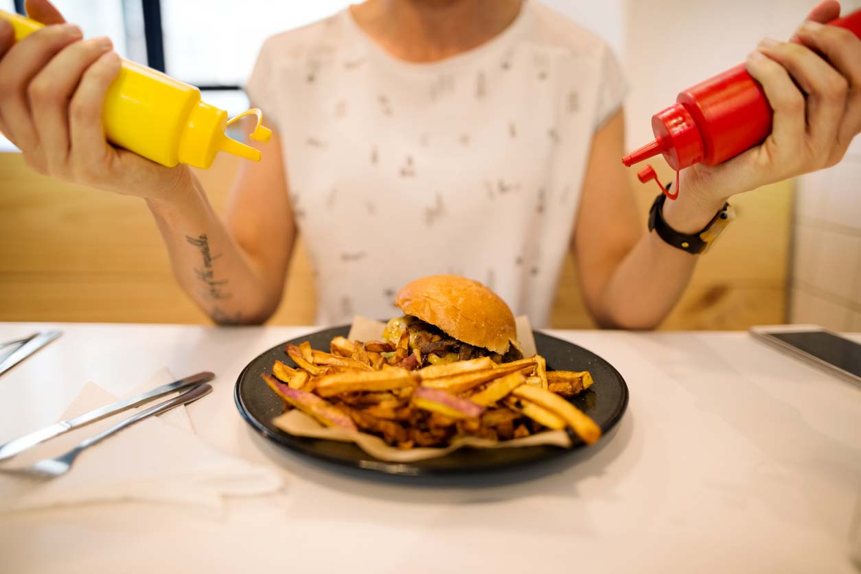 Woman putting ketchup and mustard on fast food