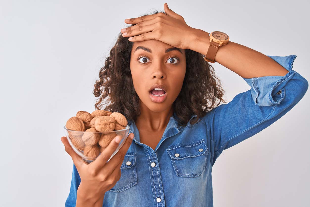 woman holding bowl of walnuts in shells