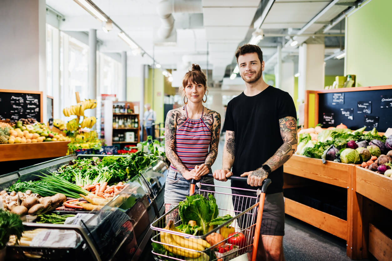portrait of hipster couple shopping for groceries at local supermarket 