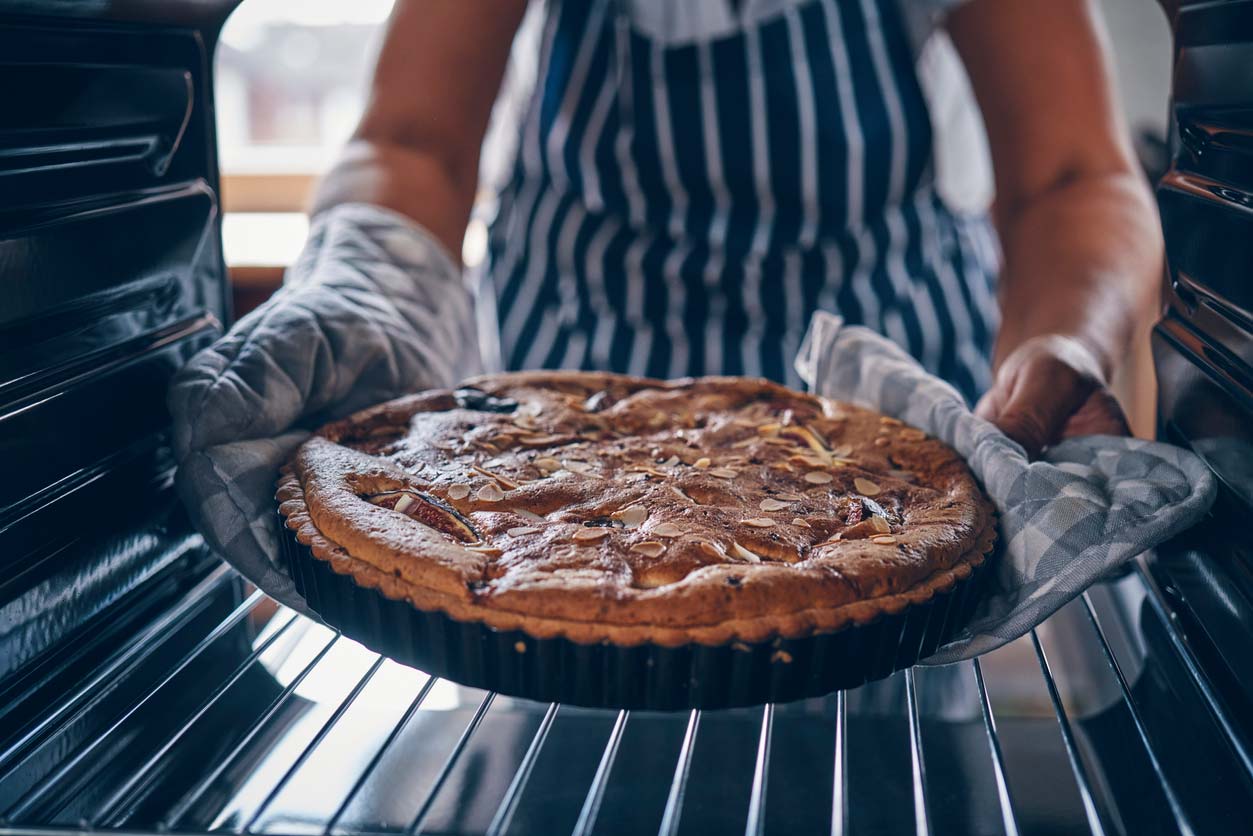 person pulling pie out of oven