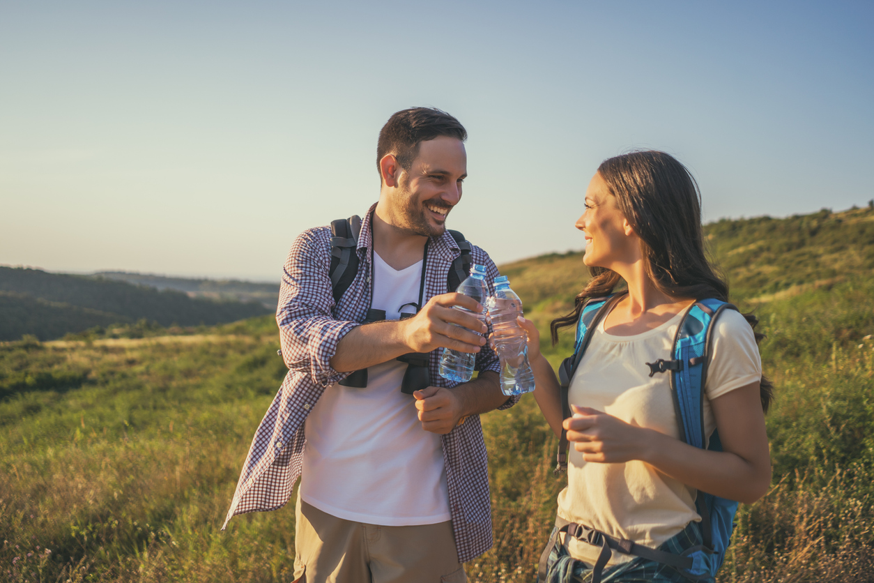 Young cheerful couple is hiking and drinking water.