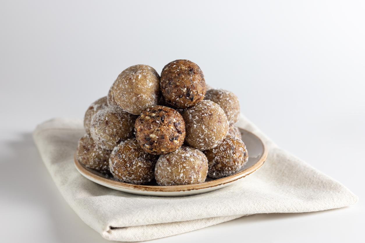 Homemade energy balls with dried apricots, raisins, dates, prunes, walnuts, almonds and coconut. Healthy sweet food. Energy balls in a plate on a white background.