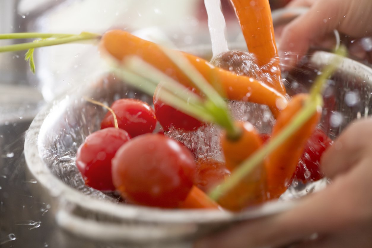 Washing tomatoes and carrots in the sink.