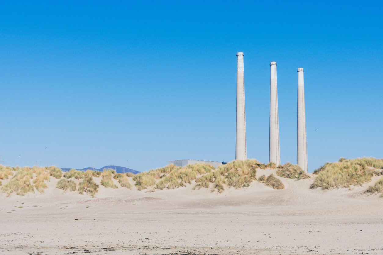 three power plant chimney pipes on a blue sky background