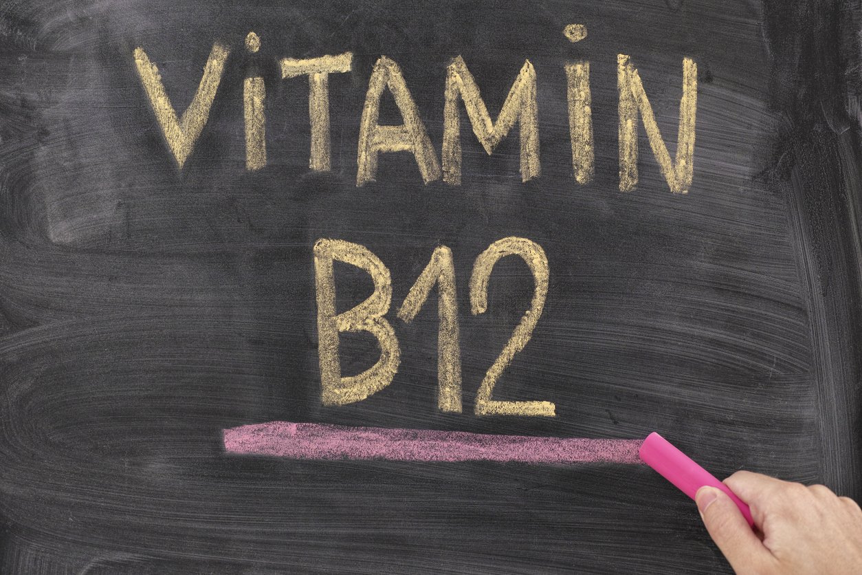 Man writing words Vitamin B12 on chalkboard. Vitamin B12 Concept. Close up.