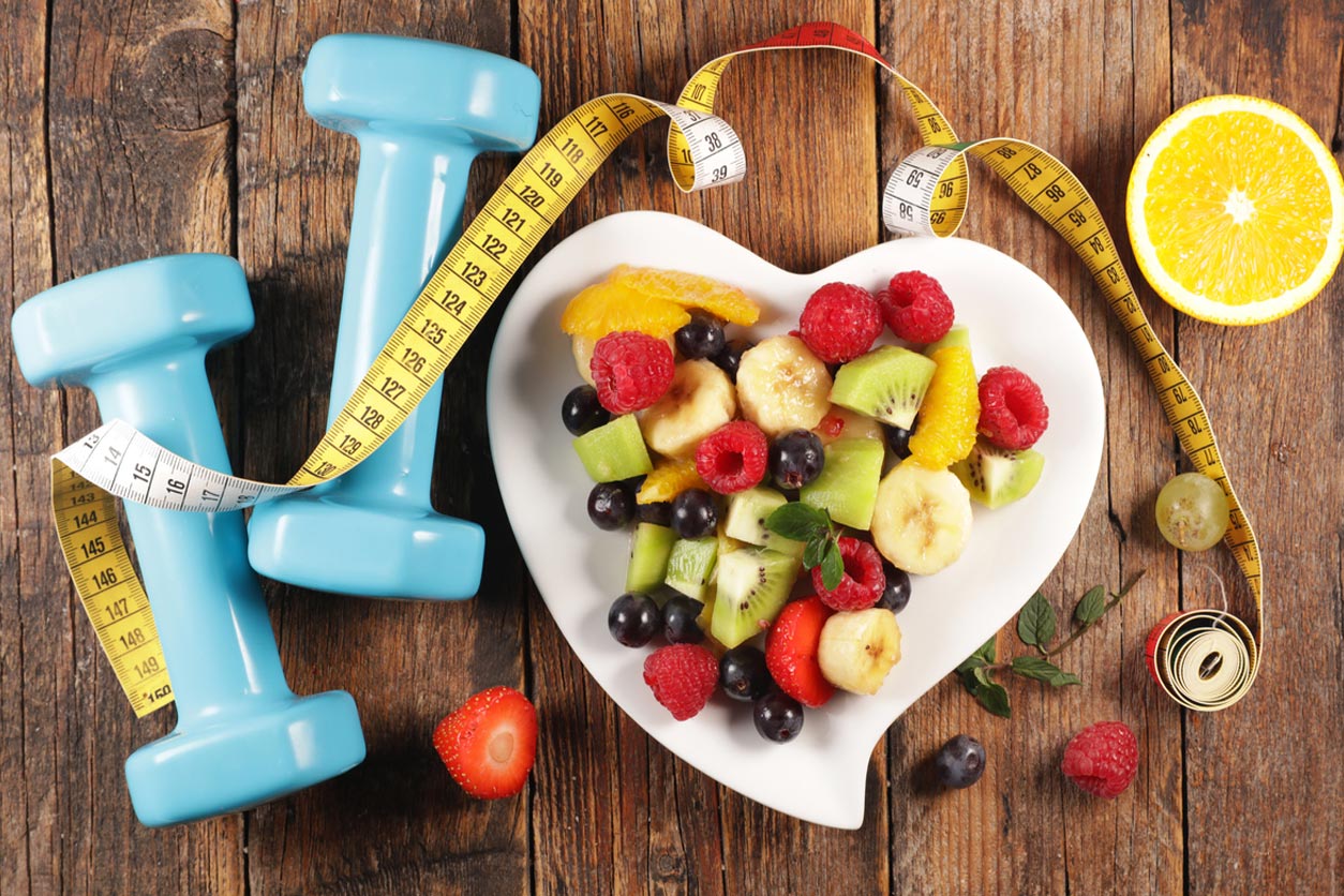 fruit on heart shaped plate surrounded by dumbbells and tape measure