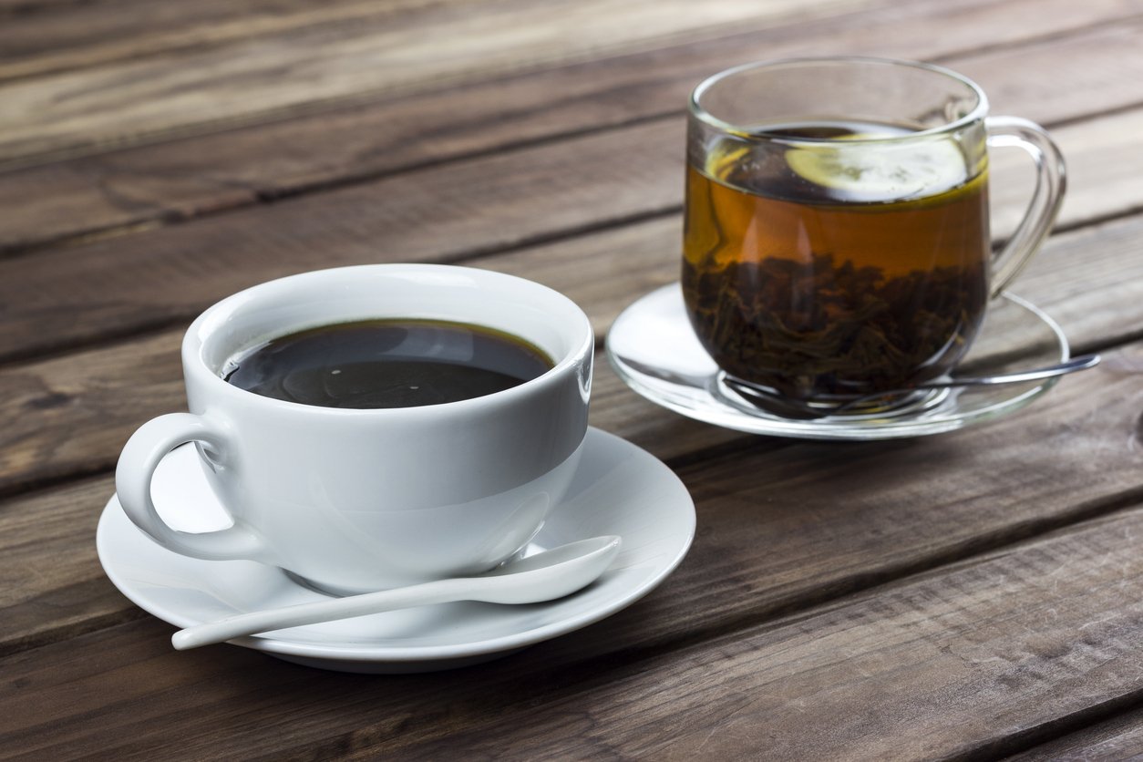 cup of tea with lemon and a cup of coffee on a wooden surface, the choice between coffee and tea