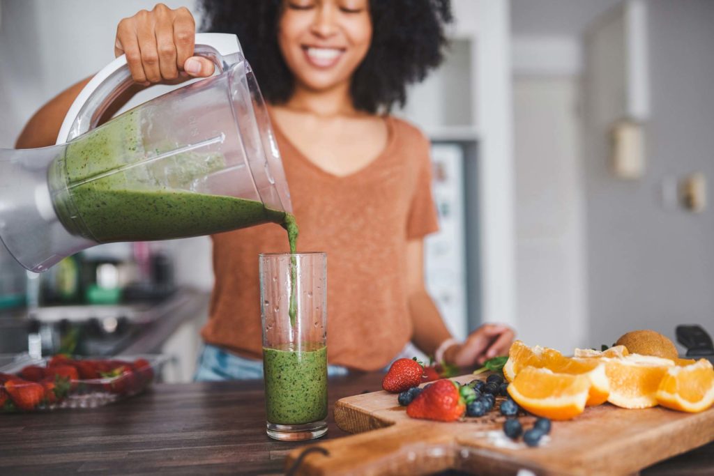 Woman pouring a green smoothie into a glass