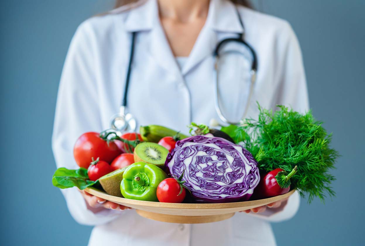 doctor holding fresh fruit and vegetables in a bowl