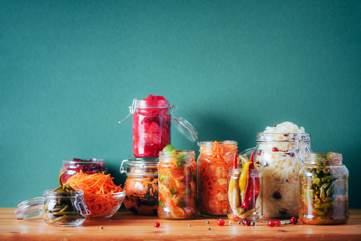 Assortment of various fermented and marinated food over wooden background, copy space. Fermented vegetables, sauerkraut, pepper, garlic, beetroot, korean carrot, cucumber kimchi in glass jars