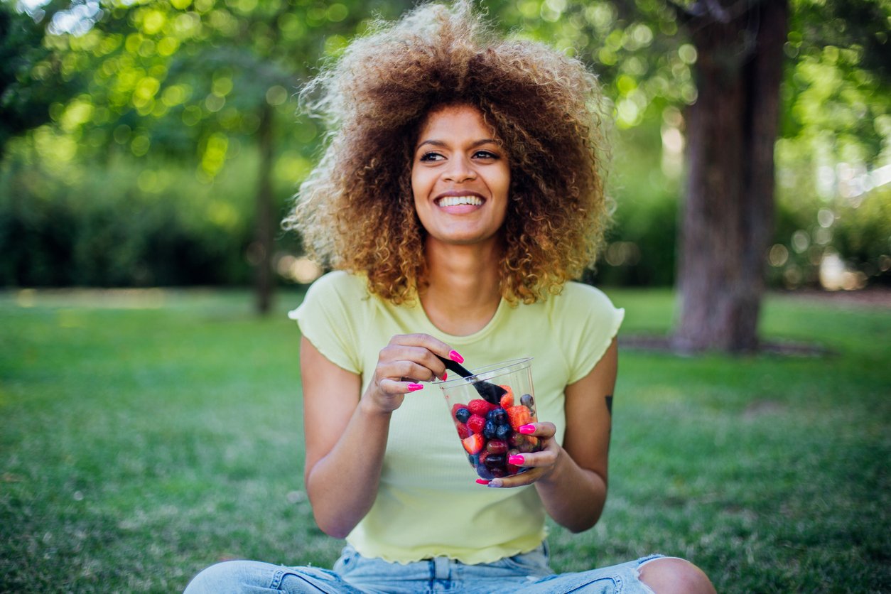 Beautiful girl resting on the grass and enjoying sweet berries