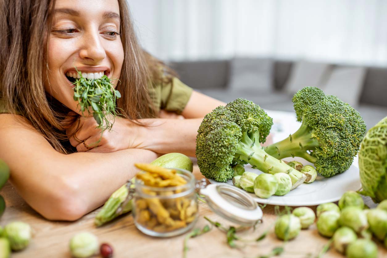 Woman with broccoli sprouts full of sulforaphane in her mouth