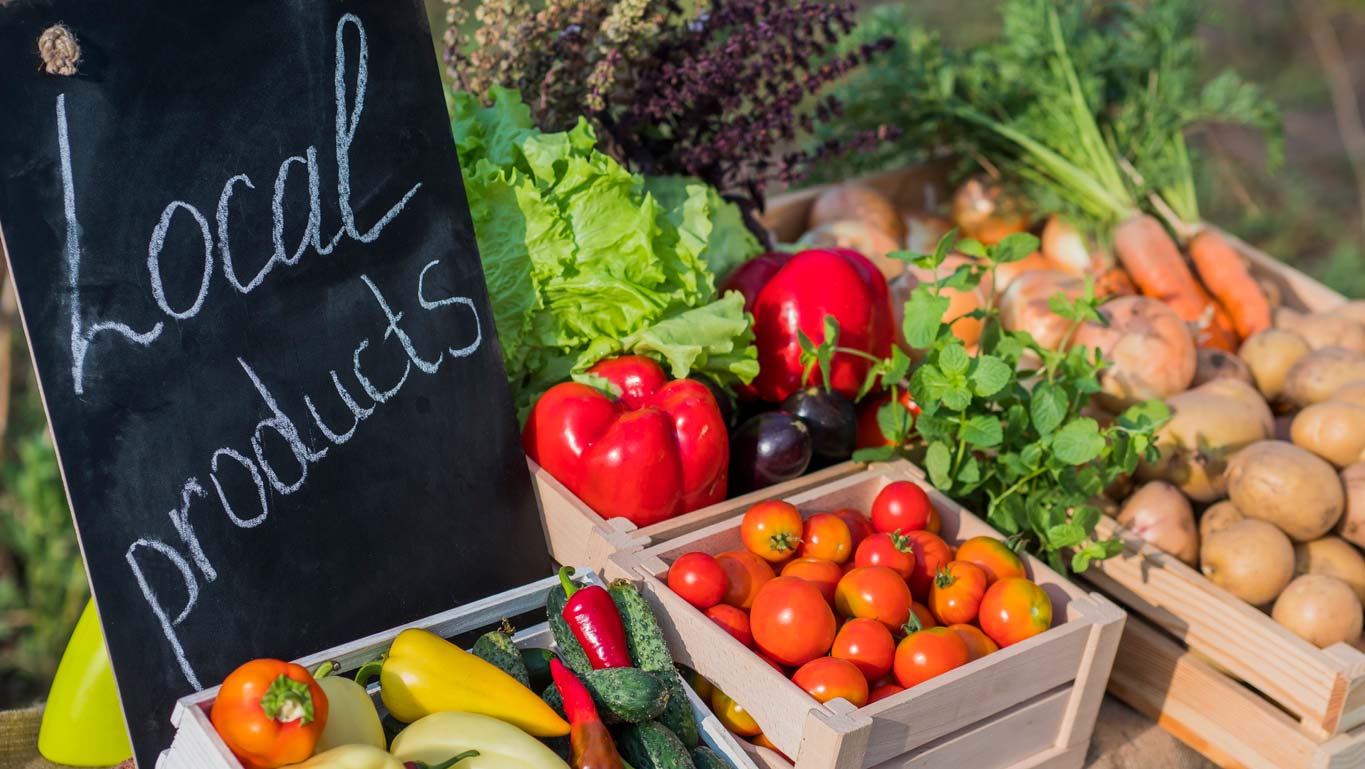 Fresh vegetables in wooden crates and a sign that says "Local products"