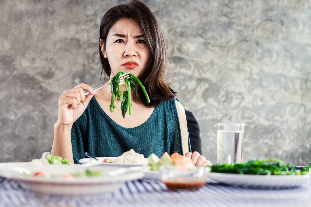 不快樂的亞洲婦女在飲食上不喜歡吃健康的食物和蔬菜