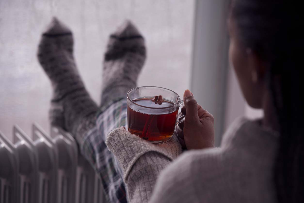 Woman holding a relaxing cup of tea and looking out a window