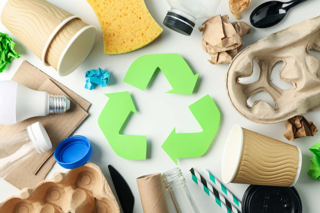 Different recyclable items surrounding the universal recycling symbol