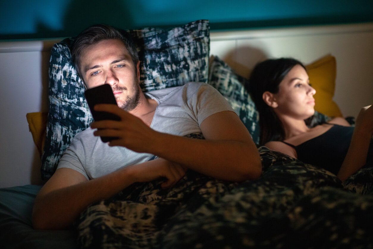 couple lying in bed and using smart phones