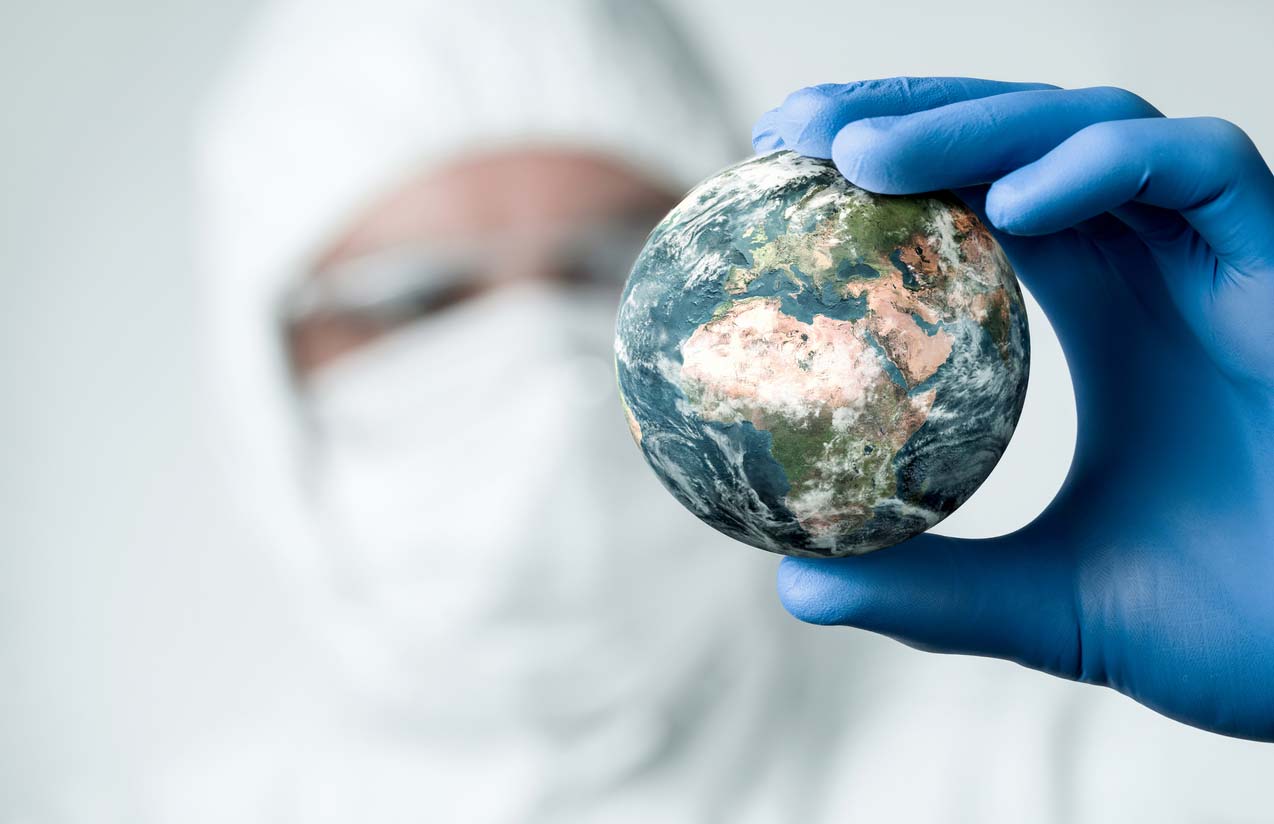 Person in ppe holding small model of the Earth