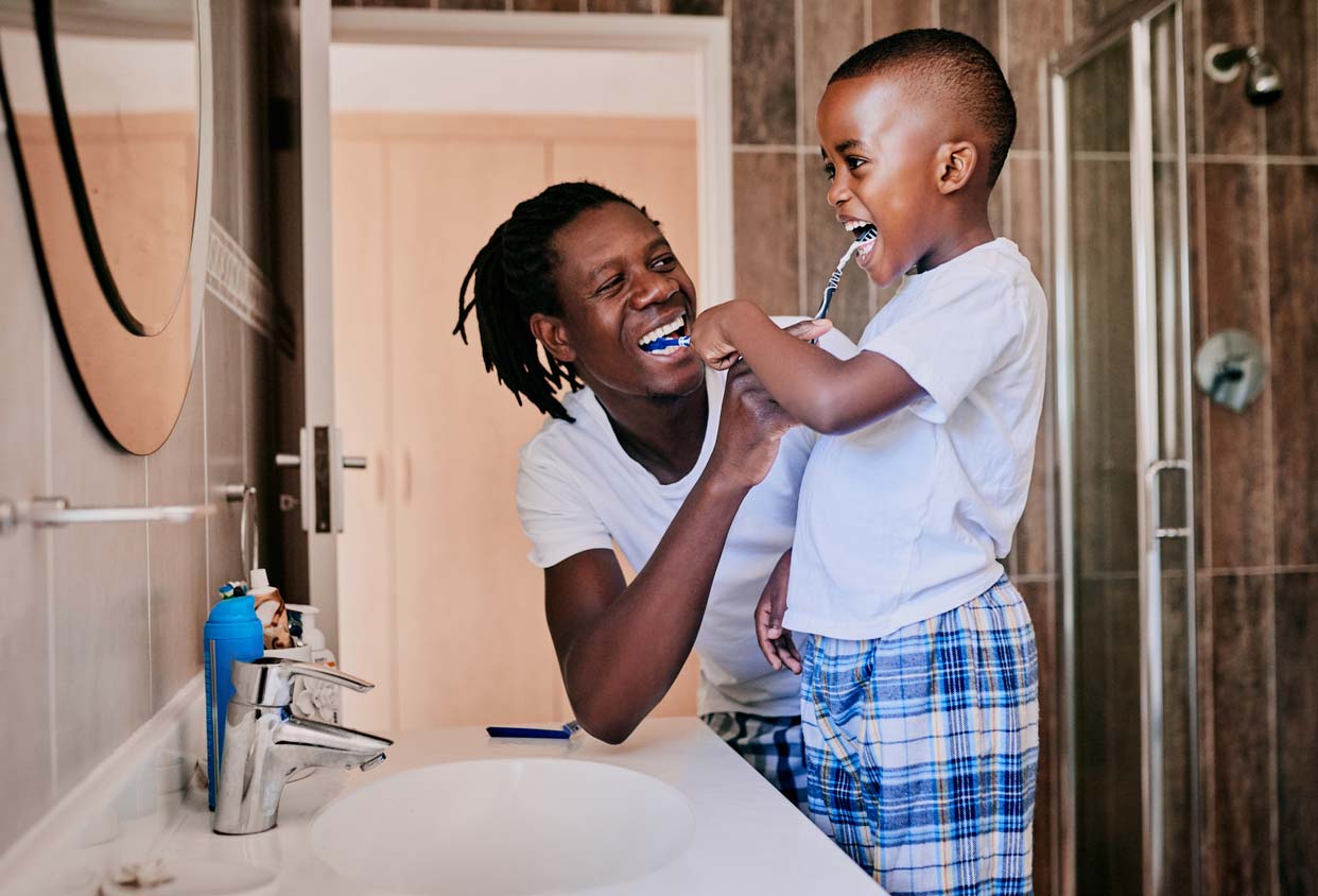 Father teaching son how to take care of his teeth by brushing